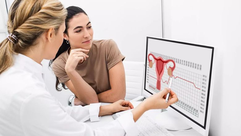 Lekarz pokazuje informacje na ekranie komputera o oznaczeniach hormonalnych w cyklu miesięcznym
